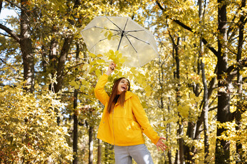 an emotional woman with a transparent umbrella in front of the autumn forest