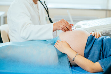Obraz premium Doctor using stethoscope for listening pregnant woman