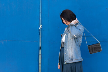 portrait of a young beautiful woman in the city, stands in a denim jacket