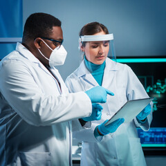Group of microelectronic engineers discussing in a modern microprocessor manufacture lab. Workplace...