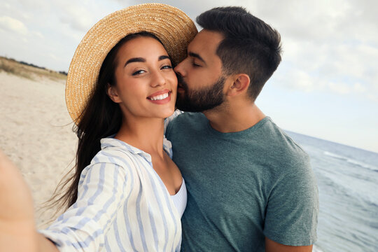 Lovely couple taking selfie together on beach - Powered by Adobe