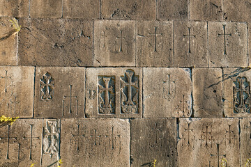 Wall of an ancient medieval Armenian church with carved crosses and other Christian attributes as a background