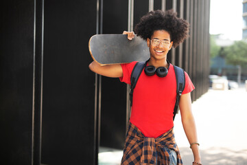 Portrait of happy african-american man with skateboard. Young fashion man with skateboard outdoors..