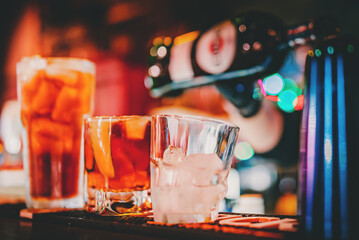 hands of a bartender with black gloves making cocktail on a bar counter.