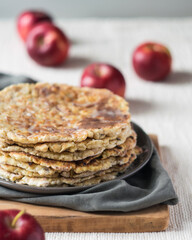 Stack of homemade whole wheat flour tortillas on a linen tablecloth with red apples in baccground, selective focus