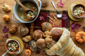 Top down view of bowls of turkey soup and a bread cornucopia with buns and rolls pouring out.