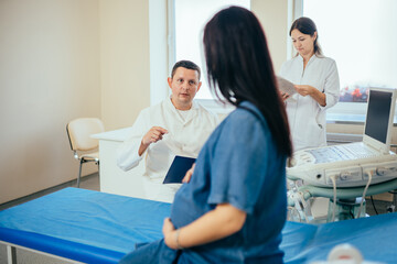 Male gynecologist consulting pregnant woman at clinic