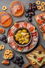 Appetizers with cocktails. Artichoke canned, olives, bruschetta with italian prosciutto cotto, crudo and figs, cheese, grape. Grey  stone surface. Vertical image.