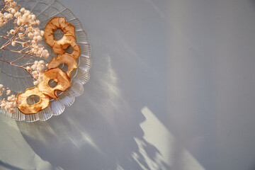 Healthy dried sliced apple chips - wholesome snacks and fresh apples on the plate. Trendy shadows....