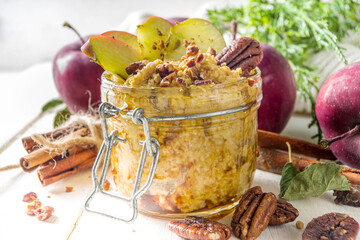 Autumn apple pecan oatmeal, overnight oats porridge with red apples, pecan nuts and caramel sauce,...