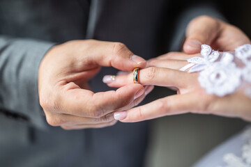 Obraz na płótnie Canvas Groom putting the wedding ring on bride finger close up.