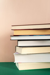 Stack of books on the table against oink background, copy space