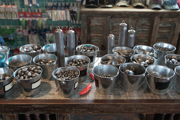 En la mesa hay muchas cubetas con mucha variedad de piezas de plomo para la pesca.
