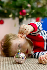 Male boy under a Christmas tree plays Christmas tree toy