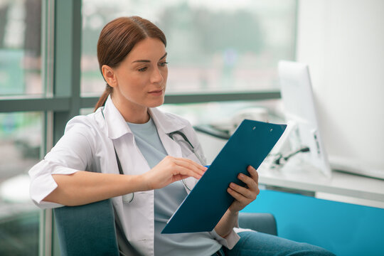 A good-looking female doctor in white robe looking thoughtful