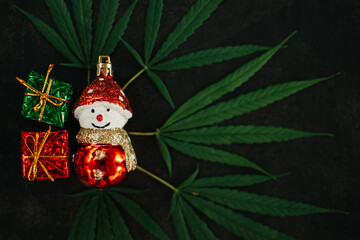 Christmas background, Christmas decor. Pattern of hemp leaves, cannabis and Christmas decorations on a dark background.