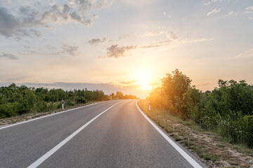 Scenic road. The road is surrounded by a magnificent natural landscape in the rays of sunset or dawn.