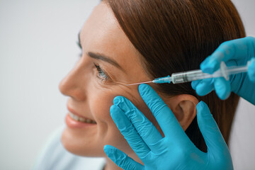 A dark-haired mid aged woman having a beaty injections procedure - obrazy, fototapety, plakaty