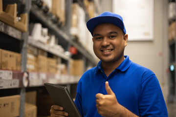 Young worker in blue uniform checklist manage parcel box product in warehouse. Asian man employee...