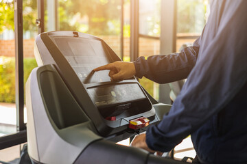 Young athlete running on the treadmill. Close up male runner exercise indoor gym. fitness man jogging wearing sportswear. Workout and healthy
