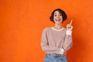 Young brunette woman smiling and pointing finger upward