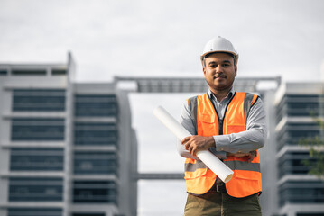 Asian engineer handsome man or architect looking forward holding paperwork blueprint with white...