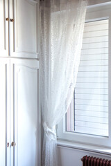 White bedroom interior. Soft light from the window illuminates the white wardrobe.