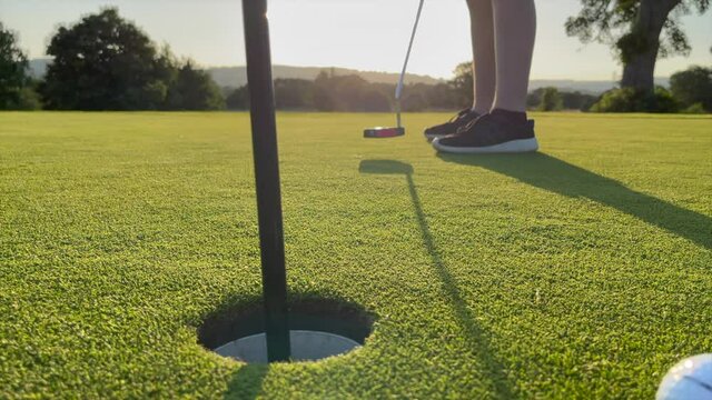 A young golfer missing the hole as he puts on a beautiful golf green