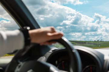 man hands on steering wheel cloudy sunny day