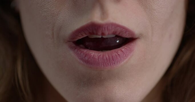 close-up of seductive female lips gently grasping grapes