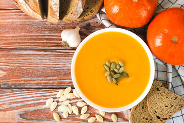 Pumpkin cream soup, orange pumpkins and rye bread on a wooden table. Preparing food from seasonal vegetables. Close-up. Top view. Place for text.