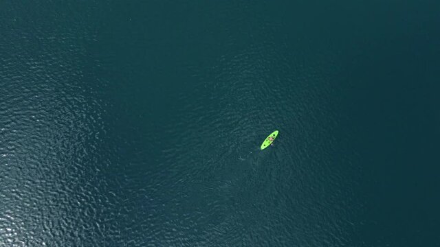 Drone shooting of SUP surfer, floating on lake.