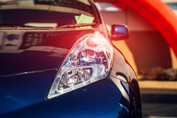 Closeup headlights of car. Blue car standing at the garage. Front view of a luxury sport car model. Element of expensive automobile