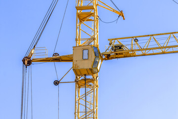 Yellow construction crane with cabin close-up against blue sky background. Concept of lifting of cargo, construction machinery and modern technology photo