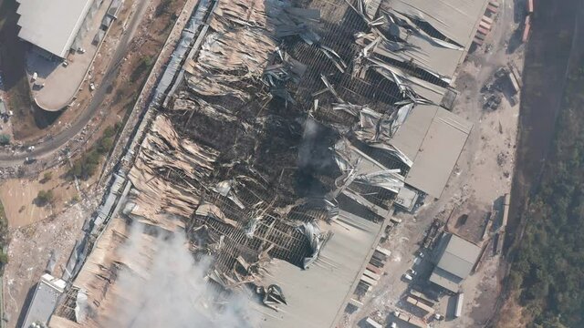 Aerial view spiraling upwards over burning, destroyed warehouse