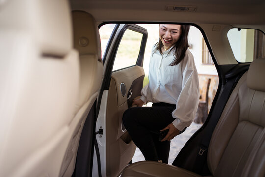 Smiling Asian woman getting into taxi