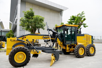 The yellow grader was parked in the company parking area