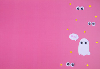 A white ghost and eyes on a pink background. Halloween Background. Flat lay.copy space for your text