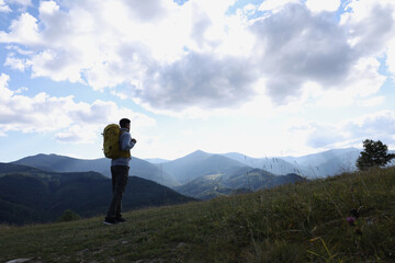 Tourist with backpack enjoying mountain landscape, space for text