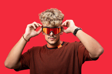 Man putting on sunglasses in red studio