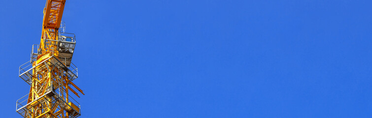 Tower building equipment construction crane cabin close-up on blue sky background, banner photo with copy space