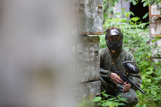Portrait of young man with face mask and gun in the action game of paintball, simulate military combat using air guns to shoot capsules of paint at each other