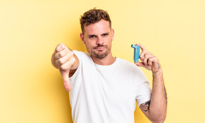 young handsome man feeling cross,showing thumbs down. asthma concept