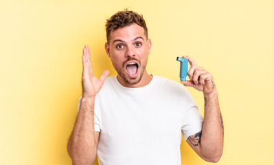 young handsome man feeling happy and astonished at something unbelievable. asthma concept