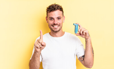 young handsome man smiling and looking friendly, showing number one. asthma concept