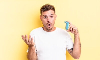 young handsome man amazed, shocked and astonished with an unbelievable surprise. asthma concept