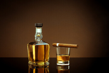 close up view of cigar, bottle of cognac and a glass aside on color back. 