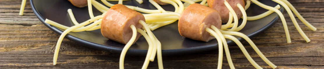 banner of spaghetti with sausages in the form of spiders. Happy kid food for Halloween party.