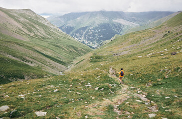Fototapeta na wymiar View of a hiker walking on a path between the mountains