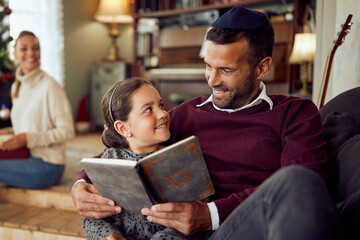 Happy father and daughter read Tanakh while relaxing on Hanukkah at home.